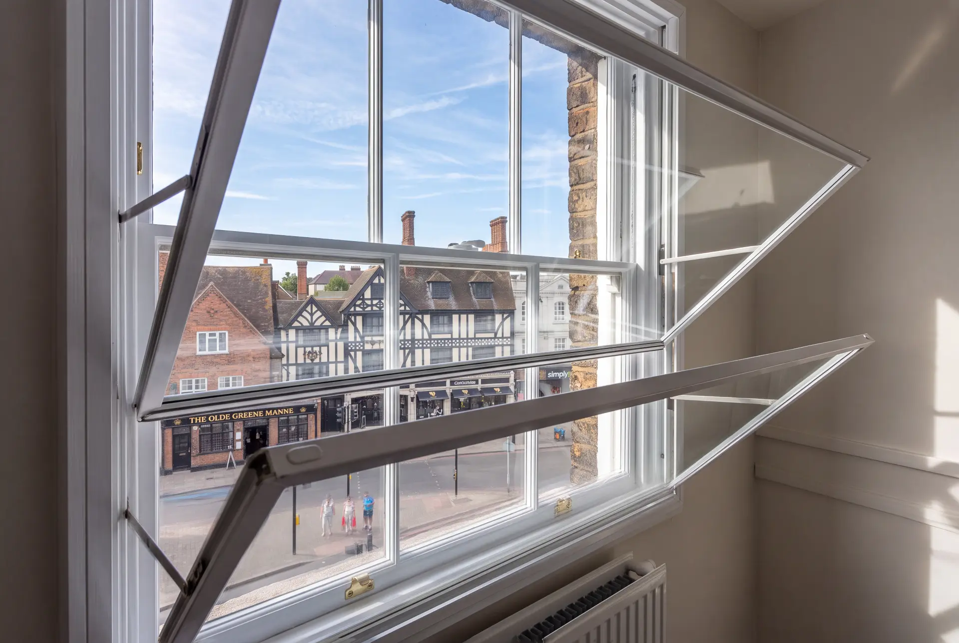 Hinged panels open — secondary glazing in Richmond, London Hinged secondary glazing panels opened inward for ventilation above a town centre street
