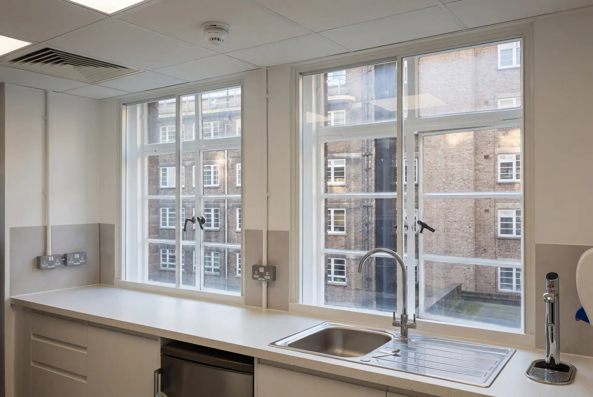 Office kitchen glazing — secondary glazing in Bloomsbury, London Office kitchen with two tall secondary glazed windows overlooking a brick lightwell