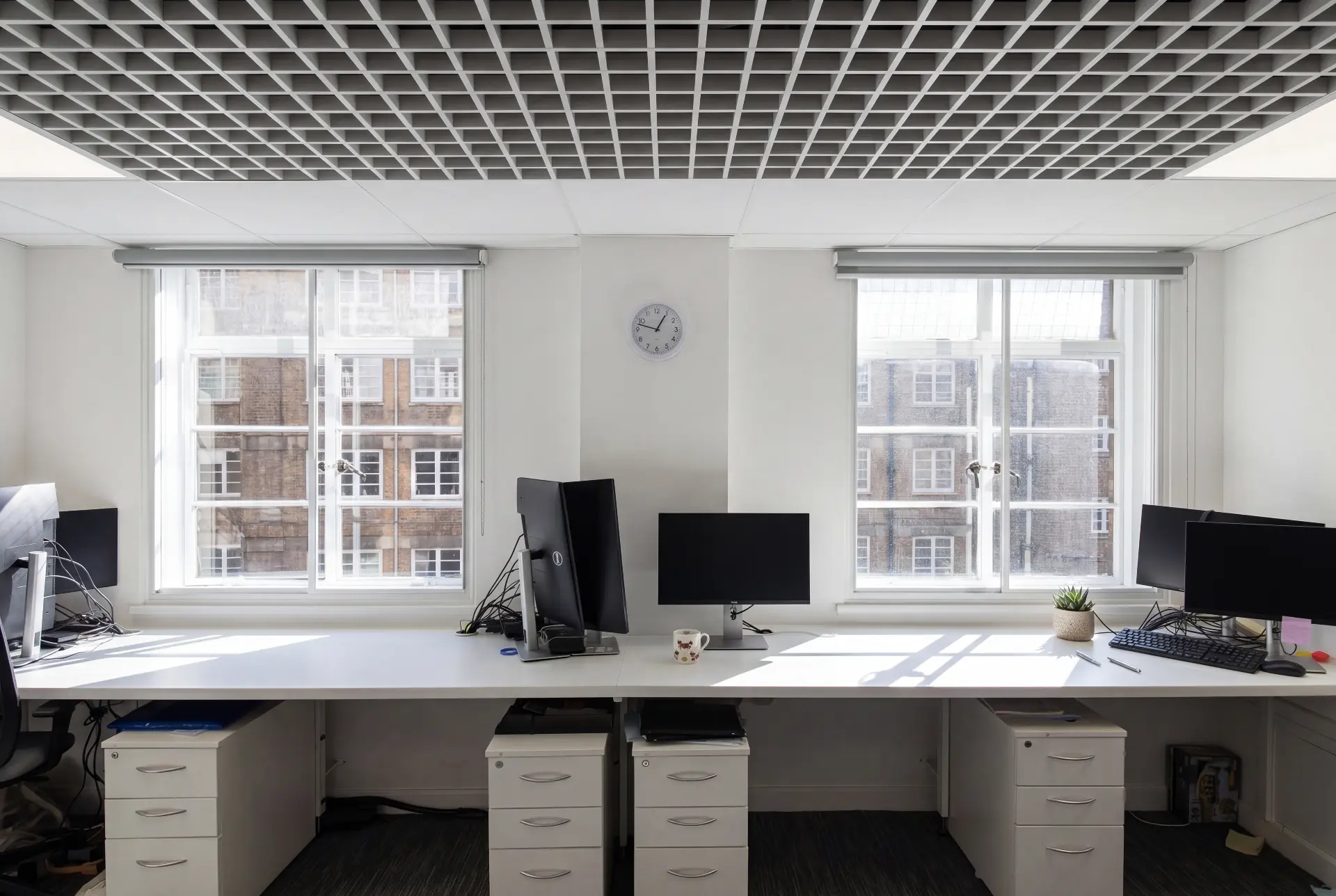 Desk bank windows — secondary glazing in Holborn, London Office desk bank between two secondary glazed windows facing a period stone facade
