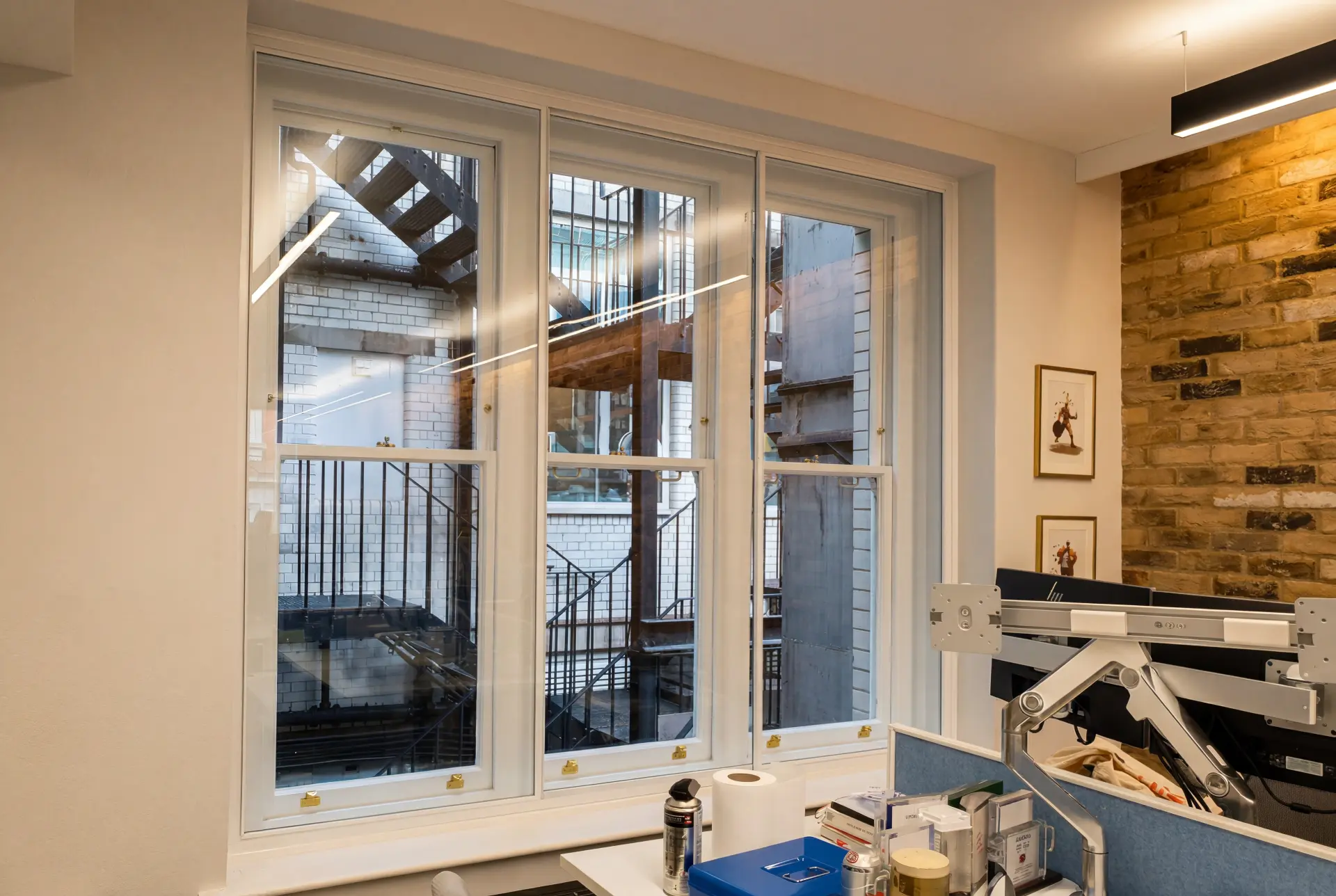 Office lightwell glazing — secondary glazing in Clerkenwell, London Office window with three-panel secondary glazing and brass fasteners facing a brick lightwell