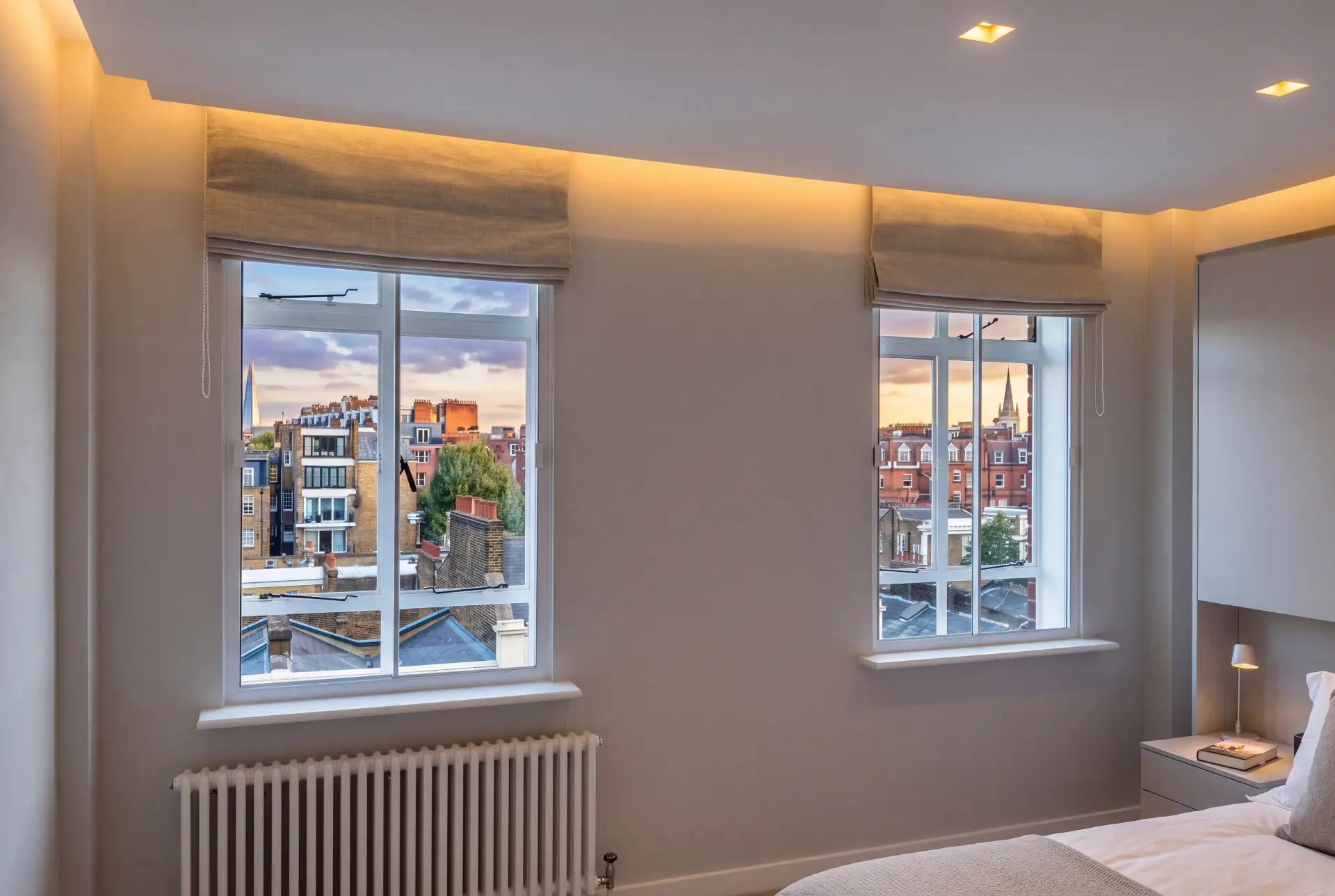 Rooftop-view bedroom — secondary glazing in Chelsea, London Bedroom with two secondary glazed horizontal sliders overlooking London rooftops at sunset