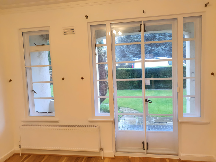Combination of secondary glazing on windows and patio doors in room with wooden floor