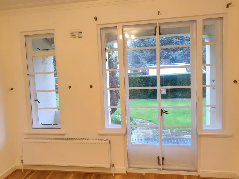 Combination of secondary glazing on windows and patio doors in room with wooden floor