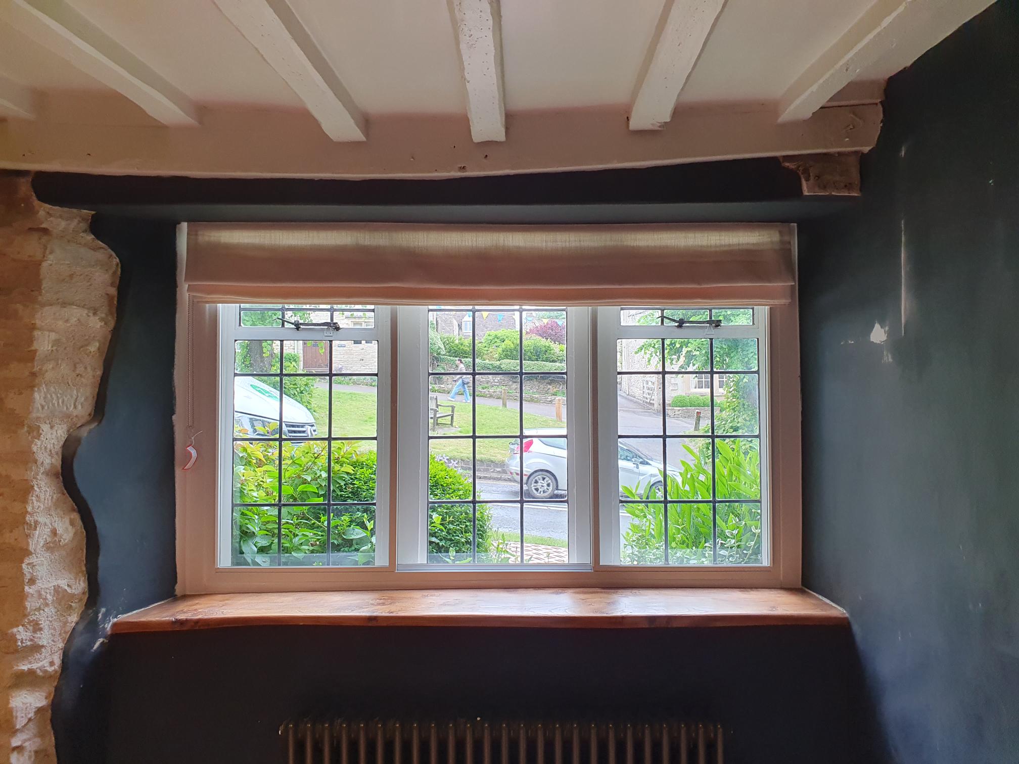 Rustic cottage window with secondary glazing featuring traditional grid design and wooden sill